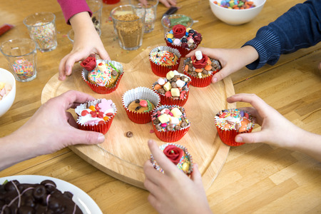 Kids picking their favourite decorated cupcake from a heart shaped cutting board at a birthday partyの写真素材