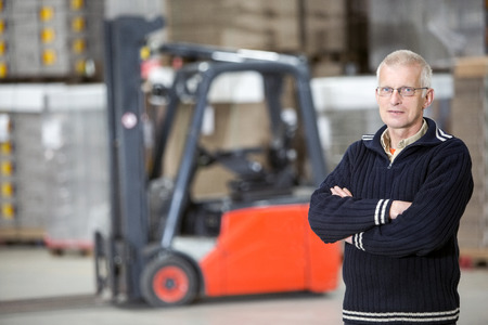 Portrait of confident supervisor with arms crossed standing at distribution warehouseの写真素材