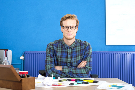 Portrait of confident designer sitting with arms crossed at desk in creative officeの写真素材