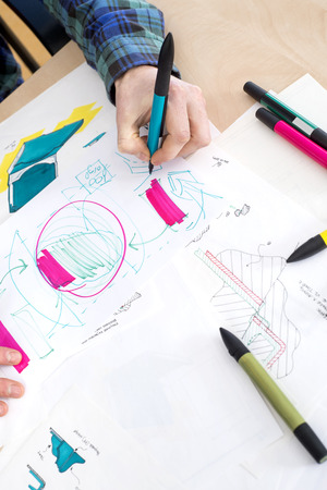 High angle cropper image of artist's hand drawing sketch on paper in creative focus