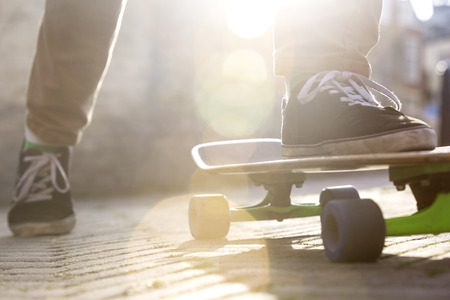 Low section of man skateboarding on footpathの写真素材