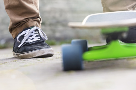 Cropped image of man with skateboard on footpath