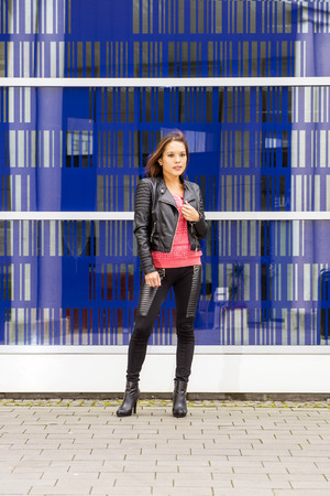 Young Asian woman, stading in front of the glass wall of a corporate building.の写真素材