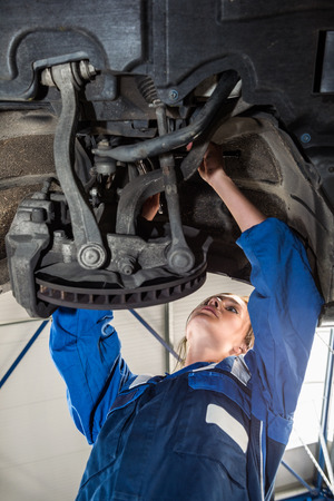 Female mechanic repairing car in automobile shopの写真素材