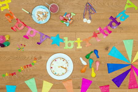 Wooden surface with an assorted array of birthday party items and objects, such as cake, candles, garlands, whistles, balloons and such, seen from above. A top view background for invitations - Happy Birthday!の写真素材