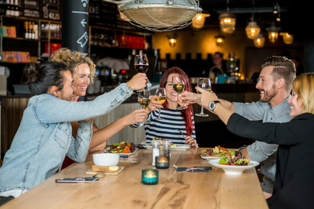 Male and female friends toasting wineglasses at restaurant tableの写真素材