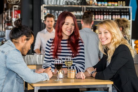 Smiling young women with male friend at table in restaurantの写真素材