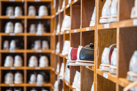 Characteristic leather bowling shoes assorted by size in wooden shelves in a bowling alley.の写真素材