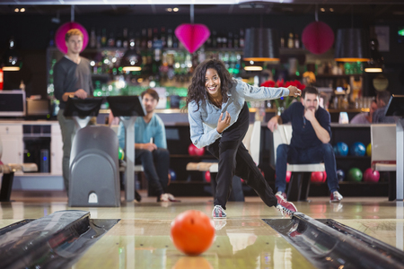 smiling woman throwed the ball at the bowling lane with her supporting friendsの写真素材
