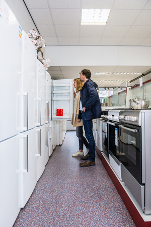 Full length of young couple buying refrigerator in hypermarketの写真素材