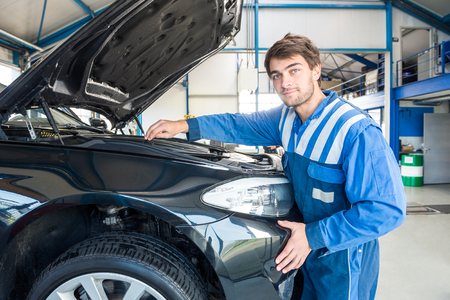 Portrait of young male mechanic repairing car engine in garageの写真素材