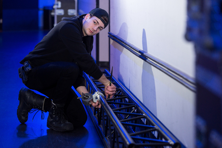 Roadie screwing a support clamp on a truss