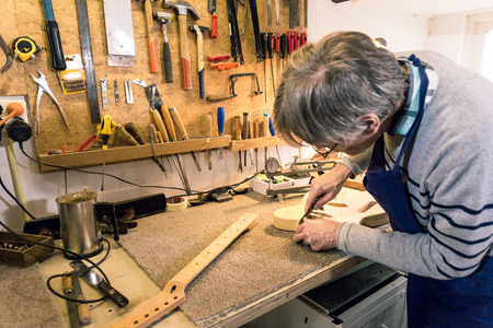Luthier carefully filing and shaping the neckpocket of an electric guitarの写真素材