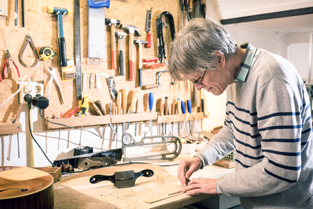 Luthier drawing the outline of a piece of bodywork for a luteの写真素材