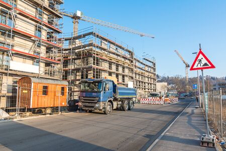 Unfinished apartment building with construction vehicles, scaffolding and construction site signの写真素材