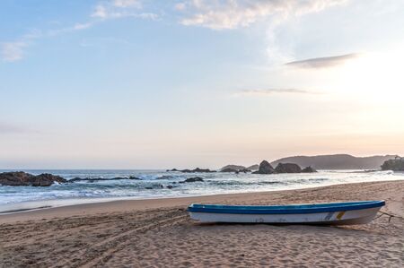 Rowing boat on a lonely sandy beach at the Pacific Ocean during the sunset