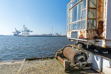 Old harbor facilities at the quay in Hamburg with container terminal in the background