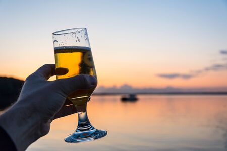 Having a fresh cold beer at a seashore during a beautiful sunsetの写真素材