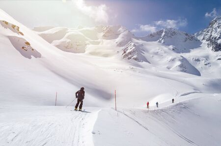 Several skiers skiing down the slope in beautiful snowy mountain landscapeの写真素材
