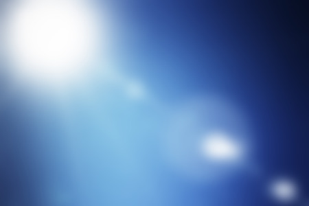 Shining summer sun flare on blue sky backgroundの写真素材