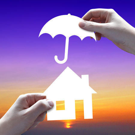 House protection concept, hands, umbrella, sunset sky in backgroundの写真素材