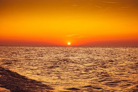 Sunset - sun reflecting in sea/ ocean, shoreの写真素材