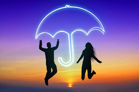 Insurance concept - umbrella, jumping coupleの写真素材