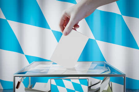 Bavaria flag, hand dropping ballot card into a box - voting/ election in Germany concept - 3D...
