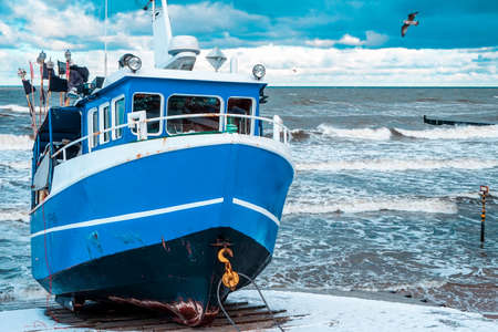 2021, December 25th, Poland, Ustronie Morskie - Blue fishing boat on a coast