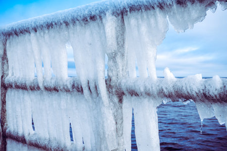 Icicles hanging on a barrier - frost, winter concept