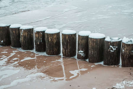 Wooden groyne on a beach covered with snow - winter timeの写真素材