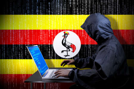 Anonymous hooded hacker, flag of Uganda, binary code - cyber attack conceptの写真素材