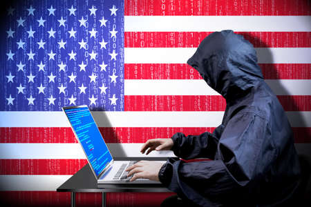 Anonymous hooded hacker, flag of United States of America, binary code - cyber attack conceptの写真素材