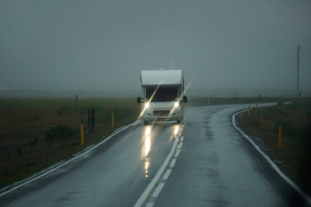 Iceland, Sudurland - August 8th, 2022 - White camper, RV driving on a road - front view