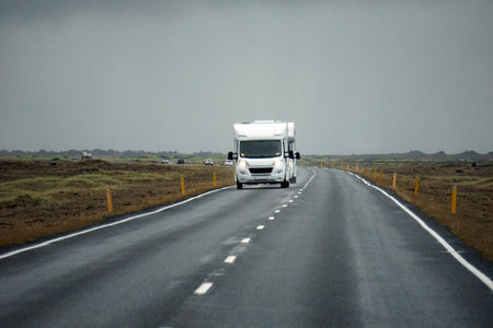 Iceland, Sudurland - August 8th, 2022 - White camper, RV driving on a road - front view