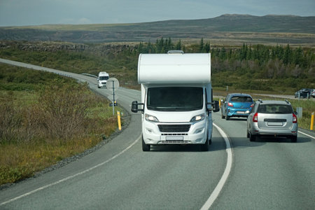 Iceland, Sudurland - August 8th, 2022 - White camper, RV driving on a road - front view