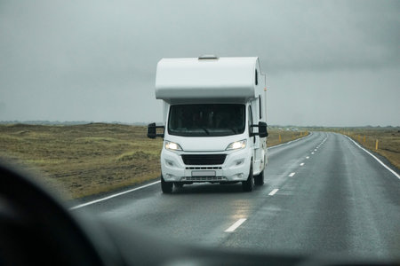 Iceland, Sudurland - August 8th, 2022 - White camper, RV driving on a road - front view