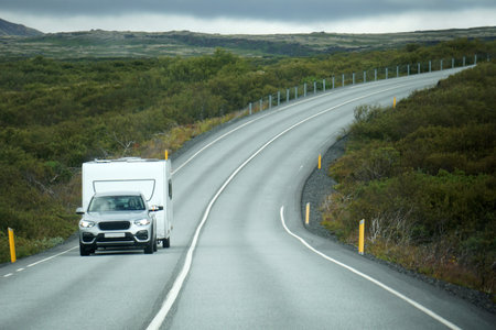 Iceland, Sudurland - August 8th, 2022 - Car towing a trailer on a road.