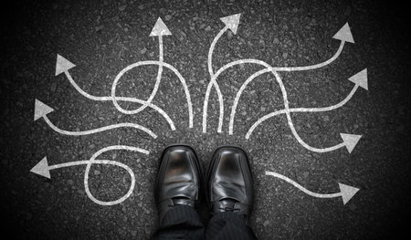 Black business shoes and many winding chalky arrows on asphalt - decision conceptの写真素材