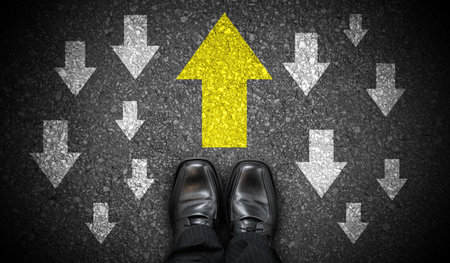 Black business shoes and chalky arrows in opposite directions - against adversity conceptの写真素材