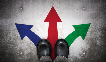 Heavy black leather boots and three colorful arrows on ground - direction conceptの写真素材