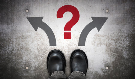 Heavy black leather boots, two arrows and question mark - problem conceptの写真素材