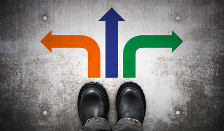 Heavy black leather boots and three colorful arrows on ground - strategy conceptの写真素材