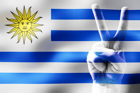 Uruguay - two fingers showing peace sign and national flagの写真素材