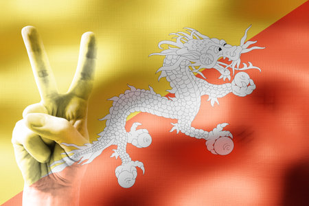 Bhutan - two fingers showing peace sign and national flagの写真素材