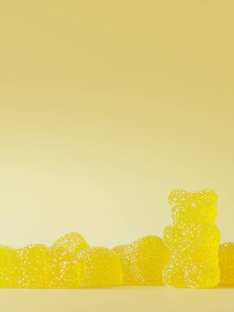 Sweet candies for happiness concept. Yellow jelly bears with sugar crystals on yellow background. 3d...