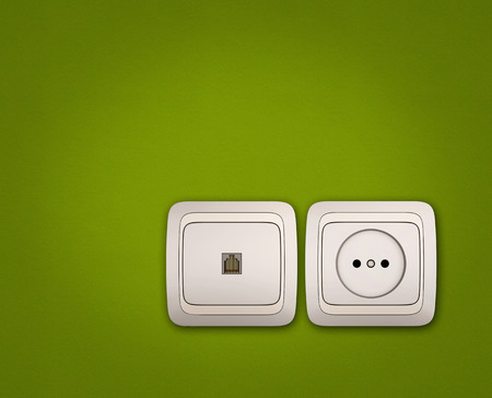Computer and electrical outlets on green wall backgroundの写真素材