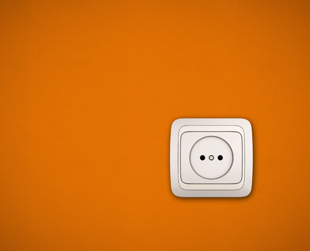 Electric socket. Simple white electric socket on orange wall.の写真素材