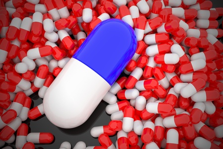 Big blue capsule lay on pile of smaller red pills.の写真素材