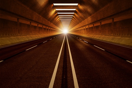Driving through a dark car tunnel. Dimmed lights with orange tint. View from the inside. May represent travel, speed, transportation or urban communication.の写真素材